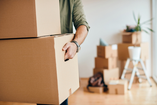 close up of a man carrying boxes out of home with boxes in the background